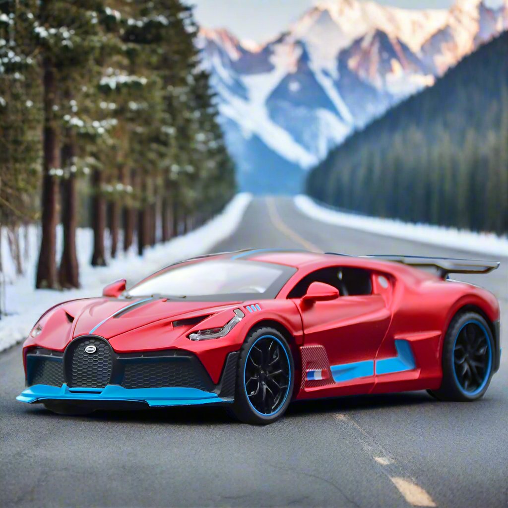 Red die-cast model of a sports car resembling a Bugatti Divo, placed on a scenic mountain road with snowy trees and majestic mountains in the background.